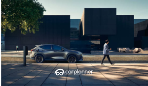 Foto tre quarti anteriore di Lexus RZ durante ricarica presso colonnina pubblica, ambiente urbano moderno